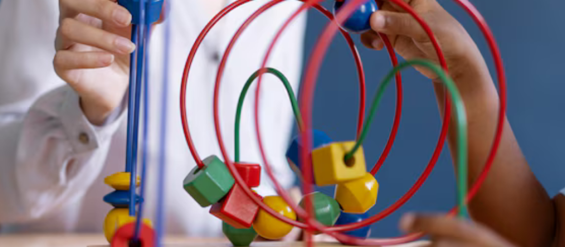 A imagem mostra uma criança e um adulto interagindo com um brinquedo de desenvolvimento infantil, um brinquedo de labirinto de contas. O brinquedo é feito de madeira e tem várias contas coloridas e fios que são passados por diferentes labirintos. A criança e o adulto estão sentados juntos em uma mesa. O foco está no brinquedo e suas cores vibrantes. A imagem transmite uma sensação de interação positiva entre um cuidador e uma criança, enfatizando o aprendizado lúdico.